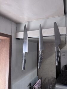 3本の包丁が磁石バーに並んでぶら下がっている様子