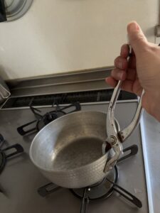 やっとこでお鍋をコンロから持ち上げているところ