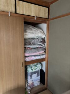 押し入れ。布団と毛布が畳まれ、下の箱にはハンカチのラベル
